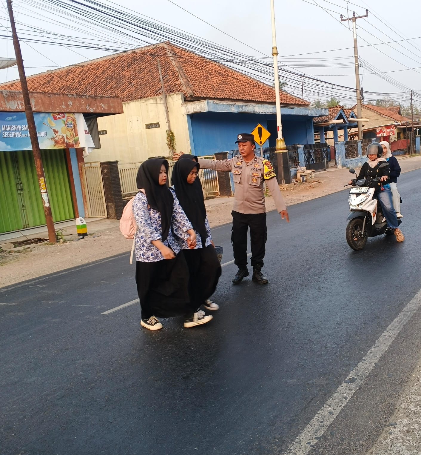 Bantu Pelajar Menyeberang, Aksi Sederhana Polisi di Tengah Ramainya Jalan